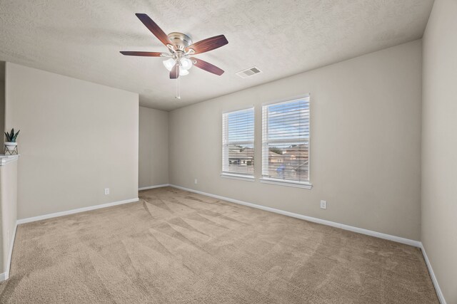 spare room with ceiling fan, light colored carpet, and a textured ceiling