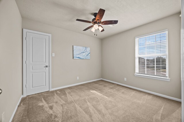 carpeted empty room with ceiling fan and a textured ceiling