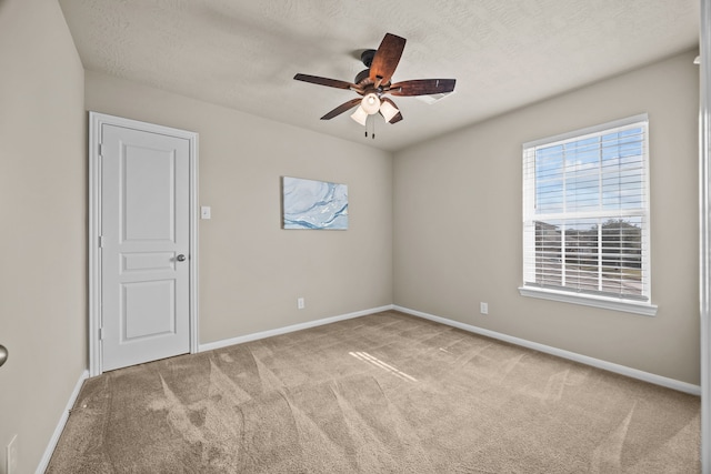 carpeted empty room with ceiling fan, a textured ceiling, and baseboards