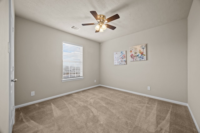 spare room featuring ceiling fan, light carpet, and a textured ceiling