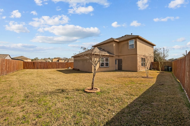 back of property with stone siding, a lawn, cooling unit, and a fenced backyard