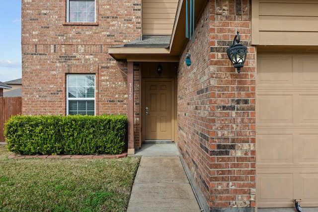 view of exterior entry with brick siding and an attached garage