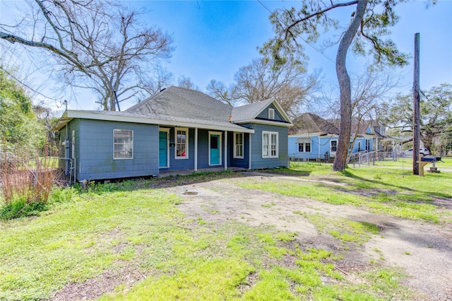 view of front facade featuring a front lawn, a shingled roof, and fence