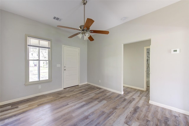 empty room featuring a ceiling fan, baseboards, visible vents, and wood finished floors