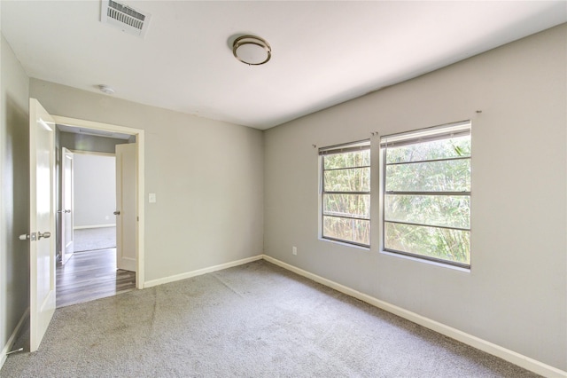 spare room featuring carpet, visible vents, and baseboards