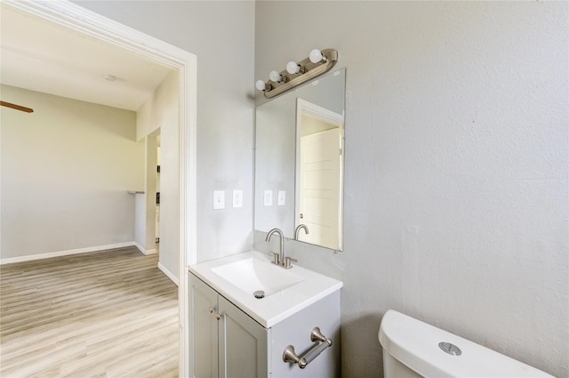 bathroom featuring toilet, wood finished floors, vanity, and baseboards