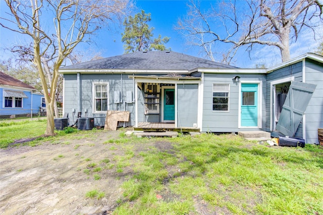 back of house with a shingled roof, cooling unit, a lawn, and fence