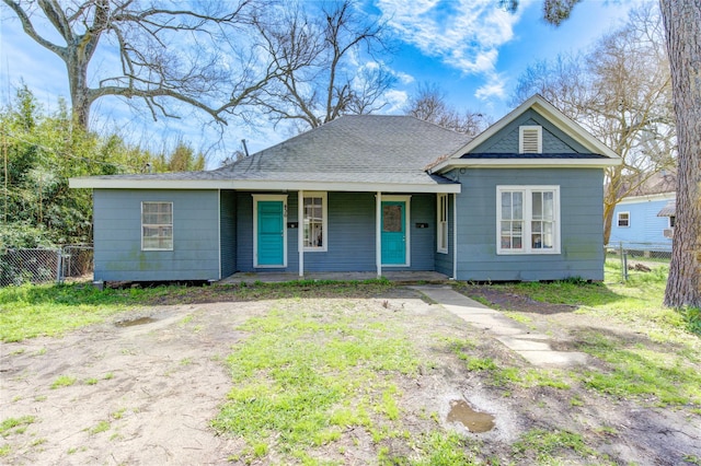 view of front of property featuring covered porch, roof with shingles, fence, and a gate