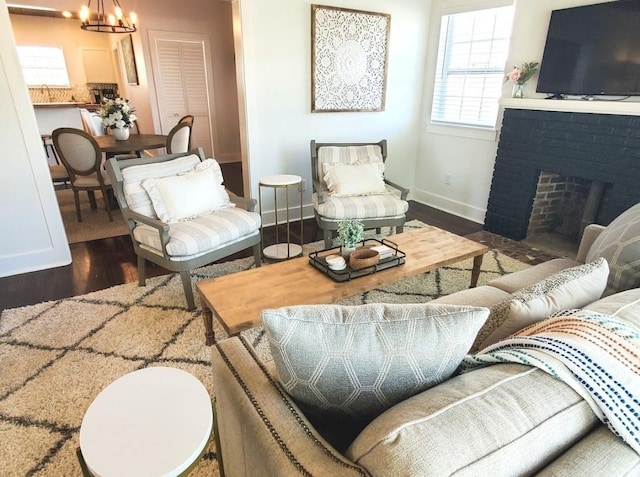 living room featuring dark hardwood / wood-style flooring, a chandelier, and a brick fireplace