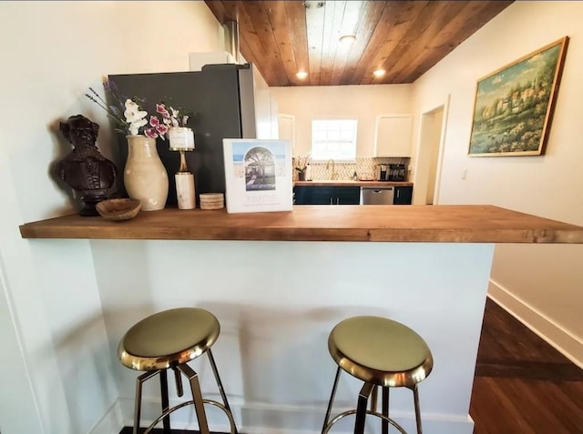 kitchen with butcher block counters, wood ceiling, and a kitchen breakfast bar