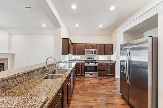 kitchen featuring appliances with stainless steel finishes, dark hardwood / wood-style floors, sink, light stone counters, and dark brown cabinets