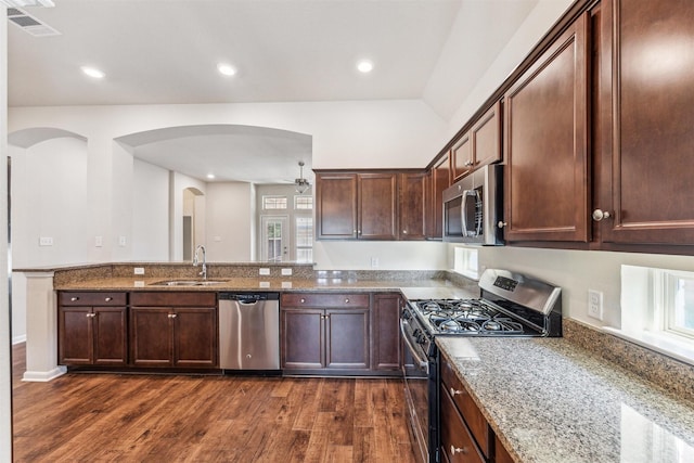 kitchen featuring dark wood-type flooring, stainless steel appliances, sink, and dark stone counters