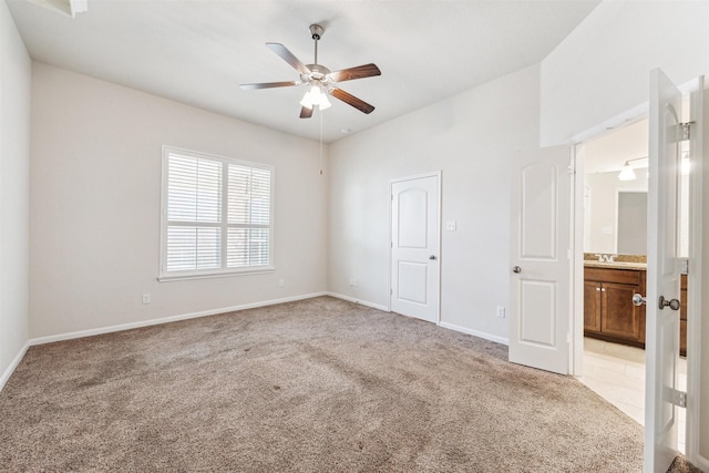 unfurnished bedroom with ceiling fan, connected bathroom, sink, and light carpet