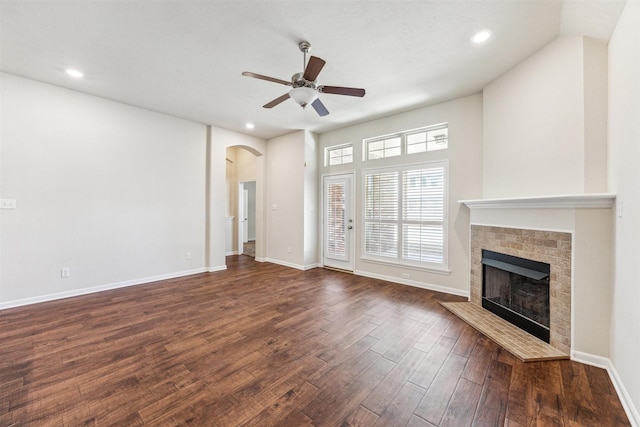 unfurnished living room featuring dark wood-type flooring and ceiling fan