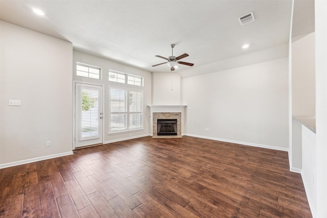 unfurnished living room with dark hardwood / wood-style flooring, a tile fireplace, and ceiling fan