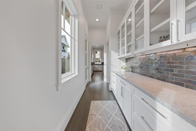 bar featuring white cabinetry, decorative backsplash, dark hardwood / wood-style flooring, and crown molding