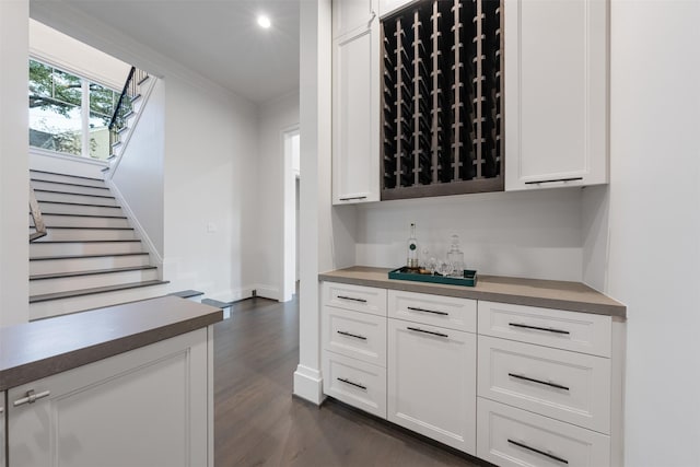 bar with crown molding, white cabinets, and dark hardwood / wood-style flooring