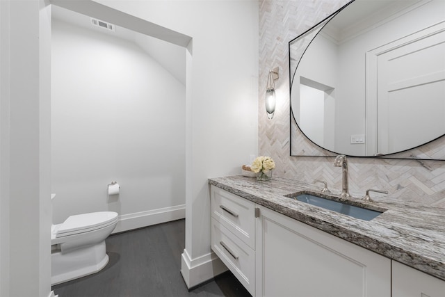 bathroom with vanity, wood-type flooring, toilet, and decorative backsplash