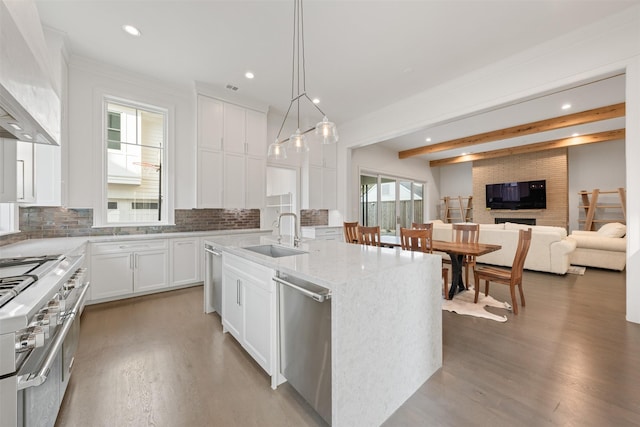 kitchen featuring sink, stainless steel appliances, white cabinets, a center island with sink, and wall chimney exhaust hood