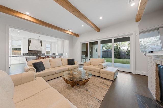 living room featuring hardwood / wood-style flooring, a fireplace, and beamed ceiling