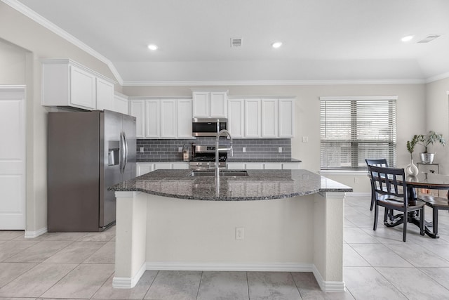 kitchen with sink, white cabinetry, stainless steel appliances, an island with sink, and dark stone counters