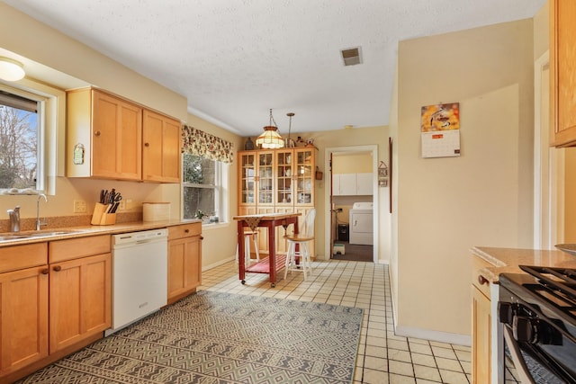 kitchen featuring pendant lighting, sink, dishwasher, a healthy amount of sunlight, and washer / dryer