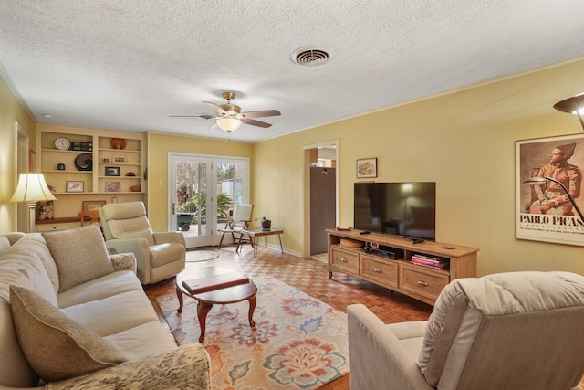 living room with light parquet floors, ceiling fan, a textured ceiling, and built in shelves