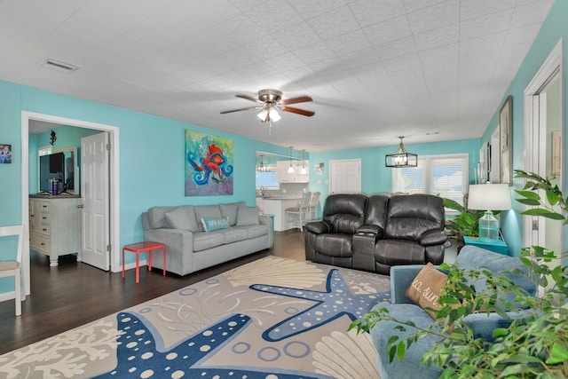 living room with ceiling fan with notable chandelier and dark hardwood / wood-style floors