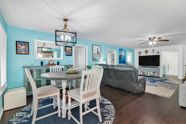 dining room with ceiling fan with notable chandelier and dark hardwood / wood-style floors