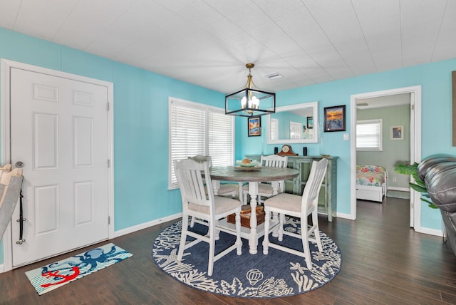 dining area with dark hardwood / wood-style flooring, a wealth of natural light, and an inviting chandelier