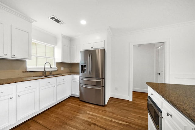 kitchen featuring sink, dark stone countertops, white cabinets, ornamental molding, and stainless steel appliances