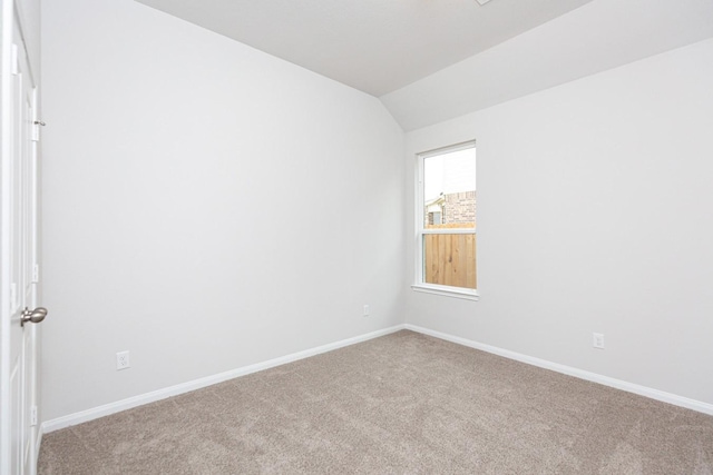 carpeted empty room with lofted ceiling