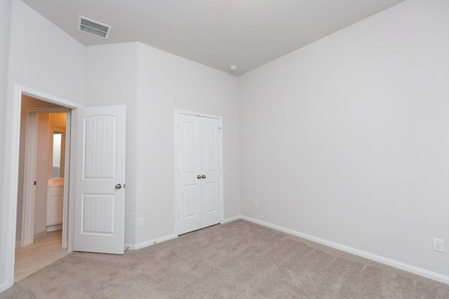 unfurnished bedroom featuring light colored carpet and a closet