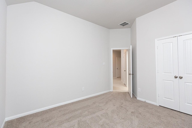 unfurnished bedroom featuring a closet, lofted ceiling, and light carpet