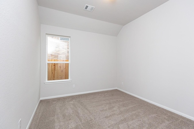 spare room with vaulted ceiling and carpet flooring