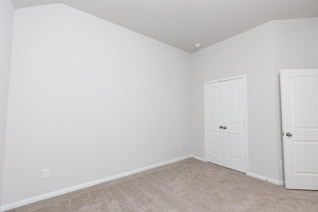 carpeted empty room with vaulted ceiling