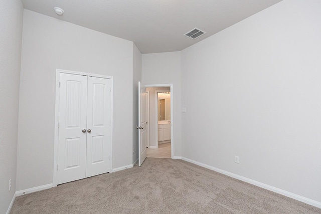 unfurnished bedroom with light colored carpet and a closet