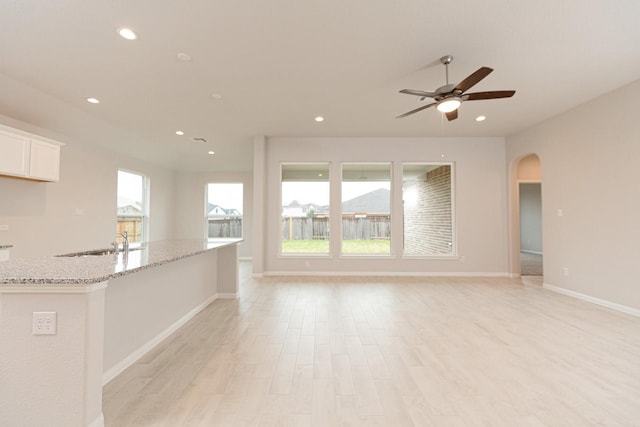 unfurnished living room featuring ceiling fan, plenty of natural light, sink, and light hardwood / wood-style floors