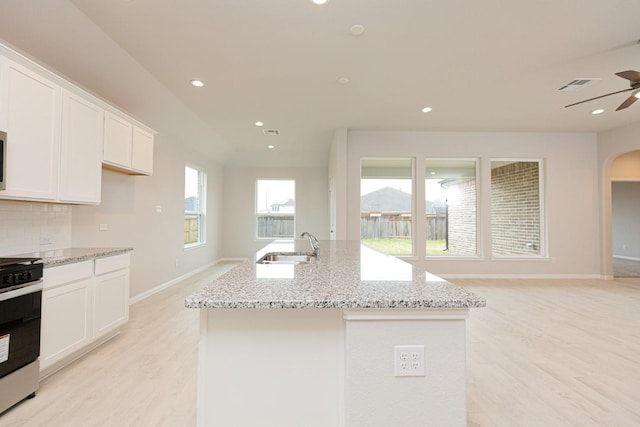 kitchen with white cabinetry, an island with sink, sink, and stainless steel range