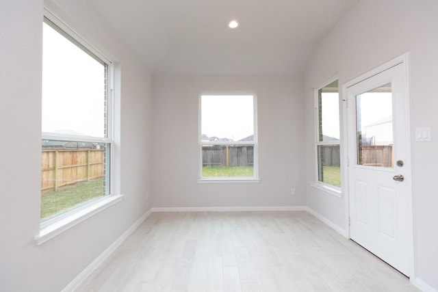 unfurnished room featuring lofted ceiling and light wood-type flooring