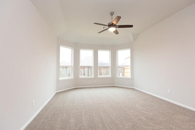 carpeted spare room with a tray ceiling, plenty of natural light, and ceiling fan