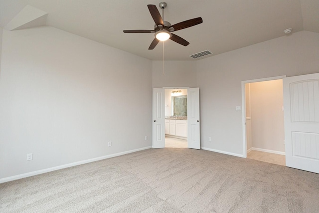 unfurnished bedroom with vaulted ceiling, light colored carpet, ceiling fan, and ensuite bathroom