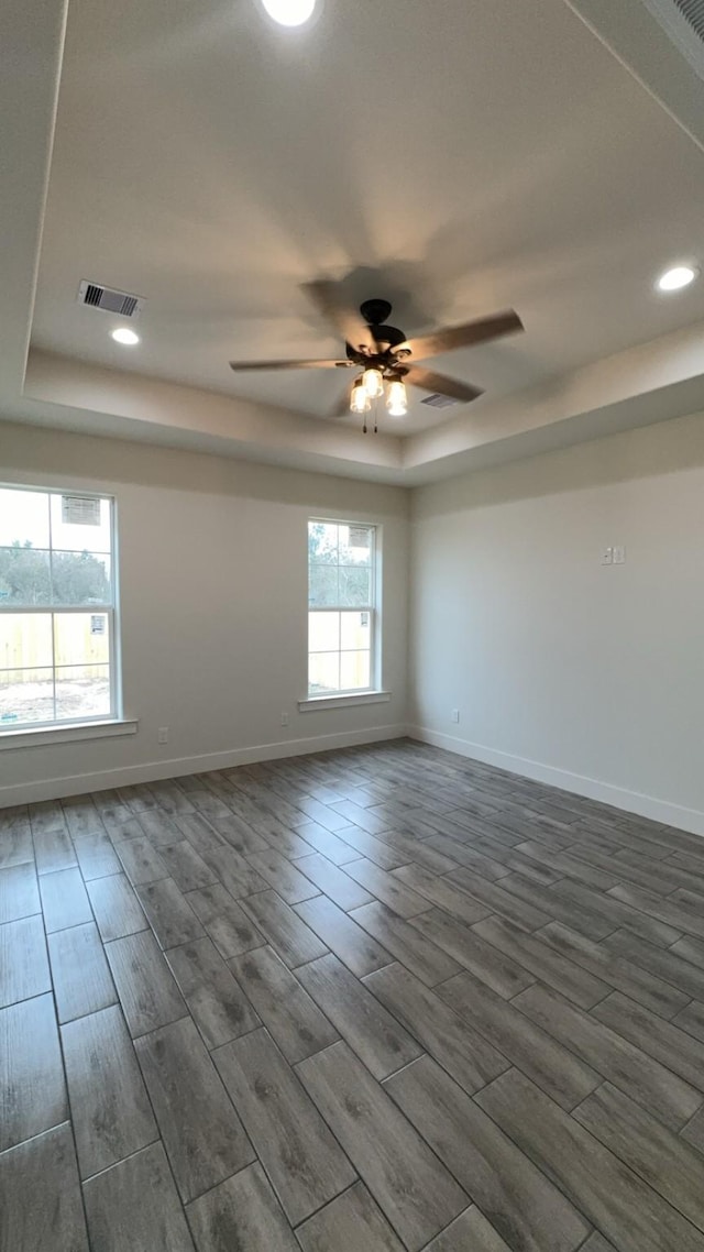 unfurnished room featuring dark hardwood / wood-style floors, a raised ceiling, and ceiling fan