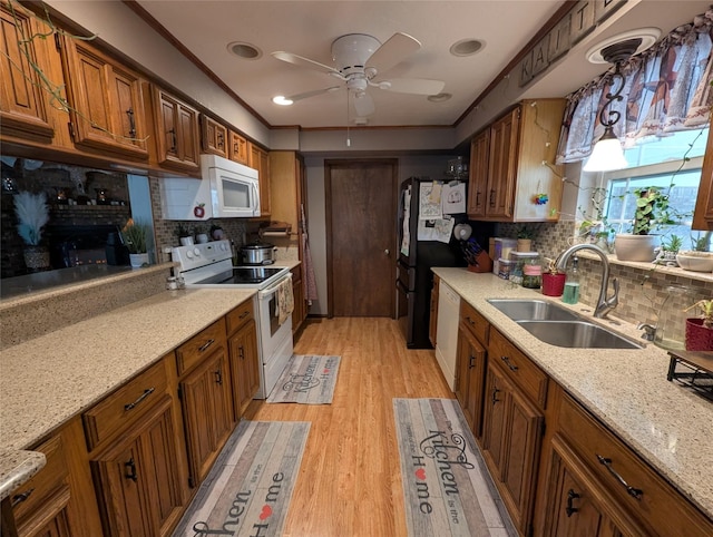kitchen with light wood-style flooring, white appliances, a sink, brown cabinets, and pendant lighting