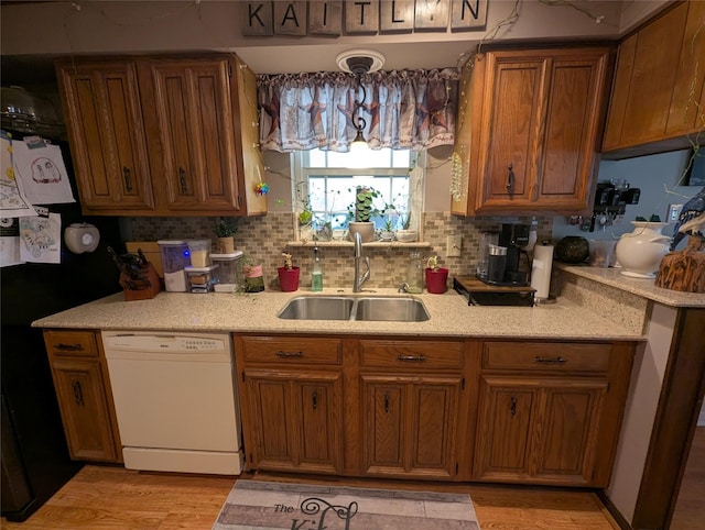 kitchen featuring dishwasher, light countertops, a sink, and brown cabinets