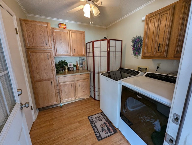 laundry room featuring ceiling fan, light wood-style flooring, cabinet space, washing machine and clothes dryer, and crown molding