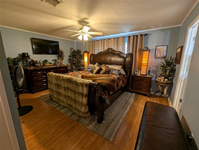 bedroom with light wood-type flooring, visible vents, crown molding, and a textured ceiling