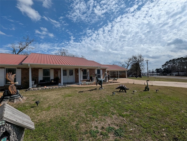 view of front of property with covered porch, a yard, metal roof, and brick siding