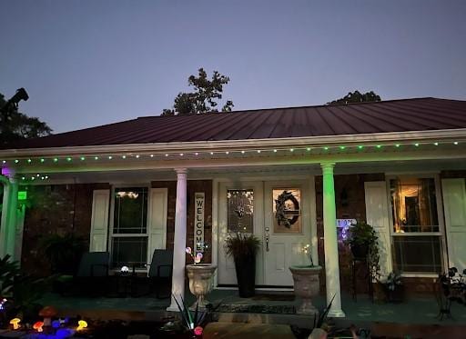 front of house at dusk with covered porch, metal roof, and a standing seam roof