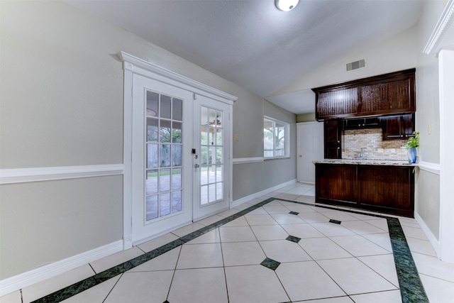 interior space with vaulted ceiling, french doors, and light tile patterned flooring